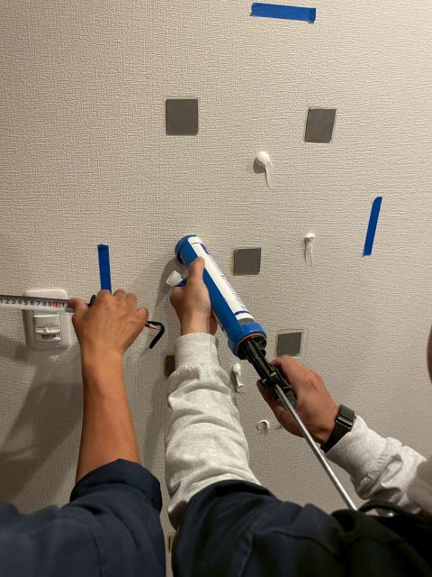 品川区大崎のマンションの廊下で壁に姿見設置工事のためコーキングする写真