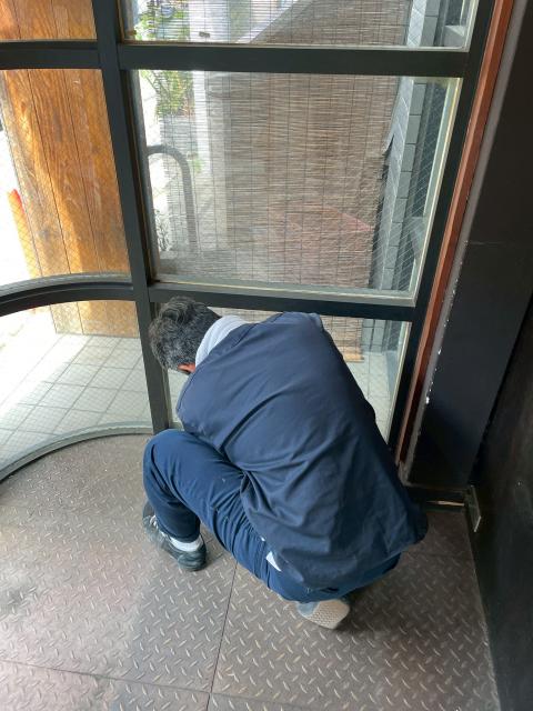 品川区戸越銀座の居酒屋さん　作業員が右側の破損したガラスを確認している写真