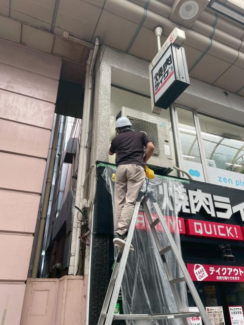 パルム商店街にある鰻屋さんでエアコン室外機洗浄作業員がビニール袋をかけている写真