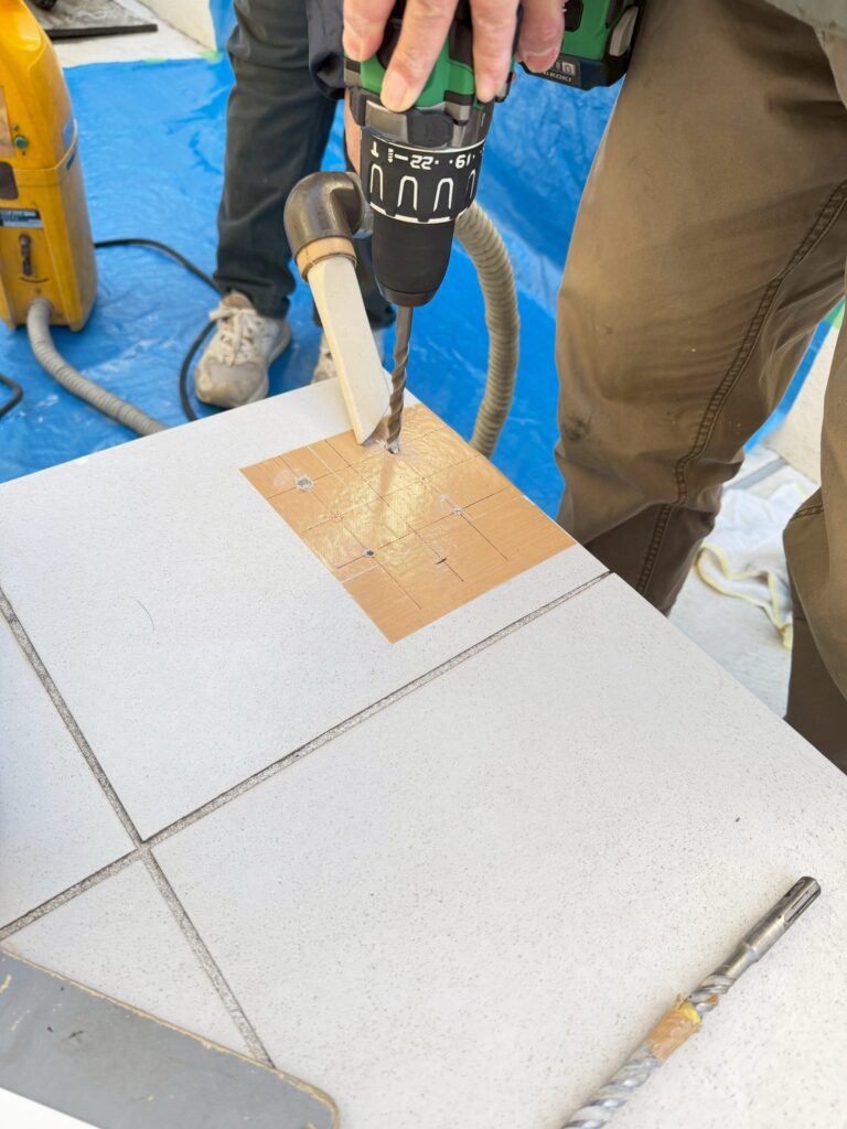 目黒区目黒本町のアパートの踊り場の手すり設置位置のマークした場所をハンマードリルで穴を開けた写真