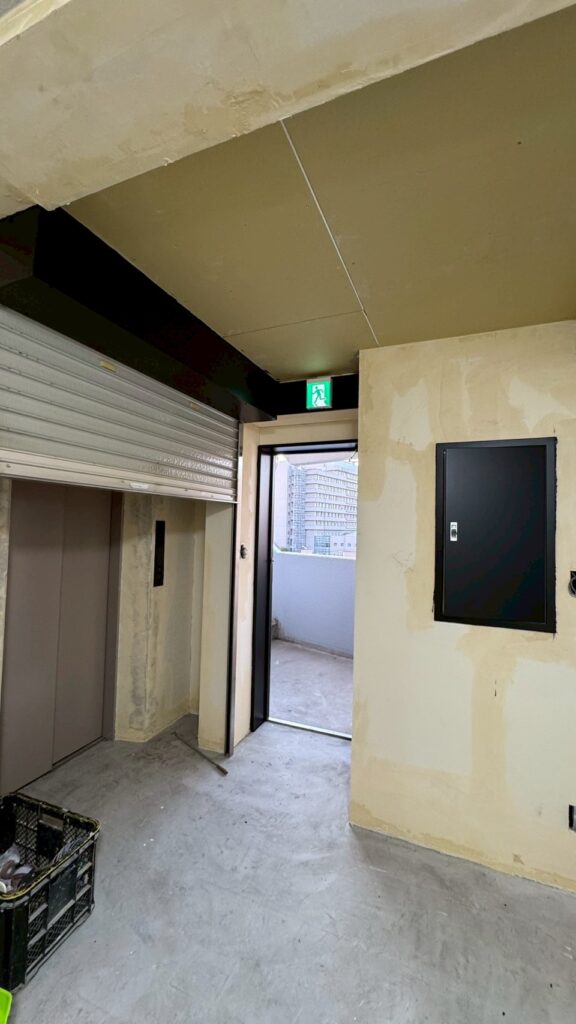品川区五反田駅近くのジムエレベーター前シャッターの上と配線ボックス黒く塗装した写真