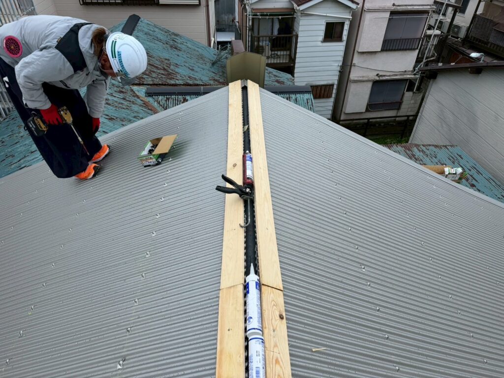 目黒本町でスタッフが棟下地の木材を屋根に取り付けて固定している写真