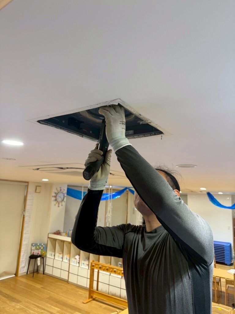 武蔵小山にある保育園の換気扇の中に手を入れている作業員の写真