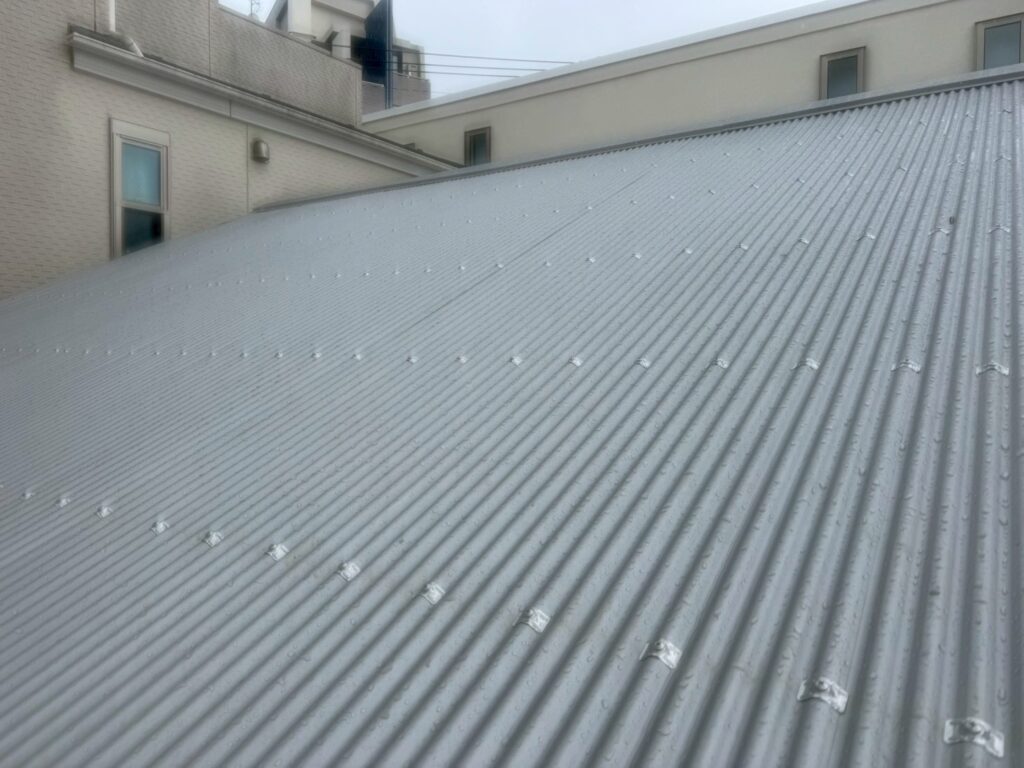 目黒本町で屋根棟板金が
全部終わり、手前波板もビス留めが等間隔に終わっている写真