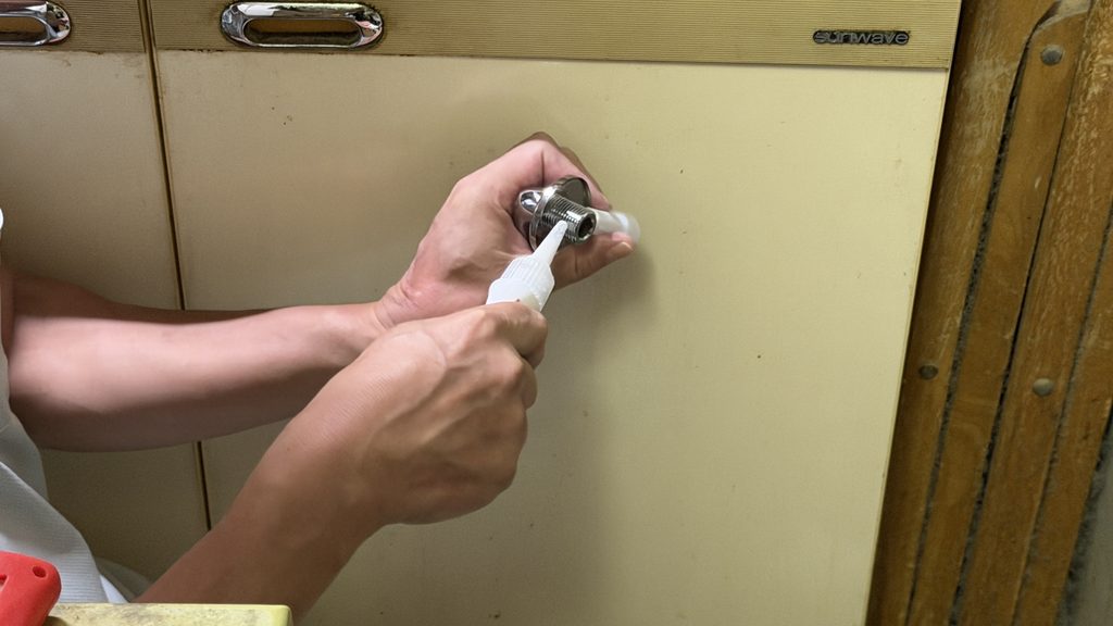 品川区小山で1階キッチンの偏心管に配管用シール材を塗布している写真